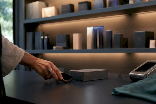 Hand holding smartphone near discreet package at checkout